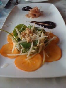 sliced persimmons under a bed of shaved pear, blue cheese and prosciutto